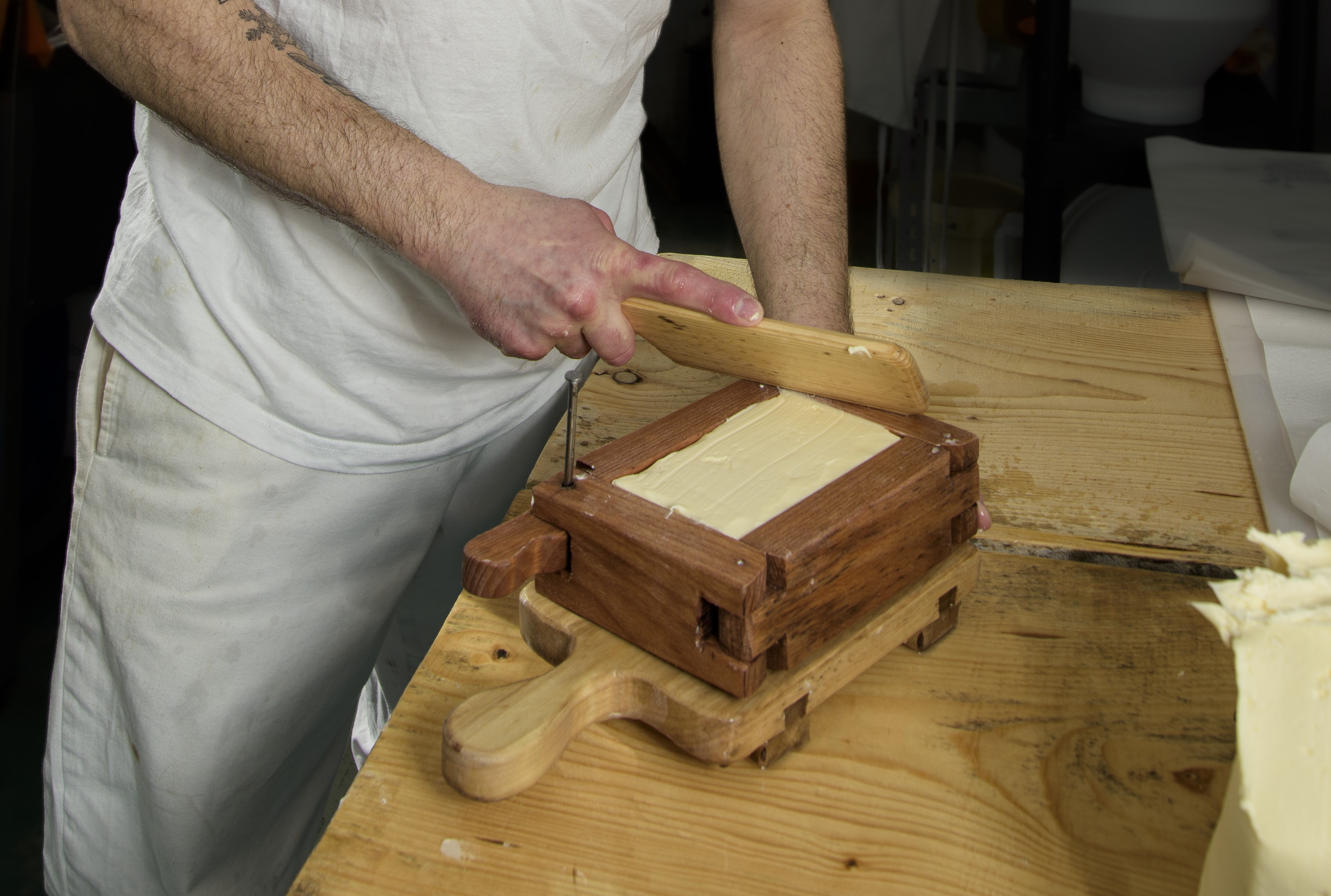 Il Casaro crea un panetto di burro utilizzando uno stampo in legno