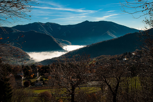 Castagneto di Caglio tra monti, nuvole e cielo azzurro.