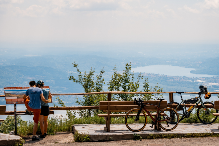 View of the Belvedere of Varese. Two bikes are resting on the benches, and two cyclists are photographing the landscape.