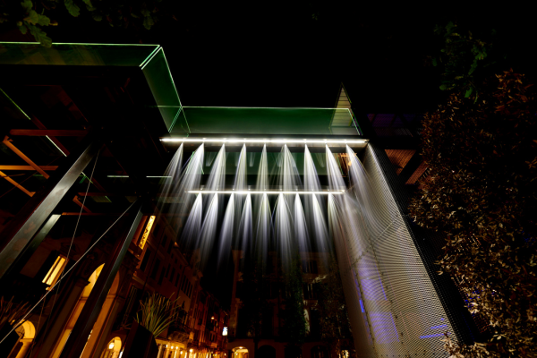 Installazione artistica con cascate di luci su una struttura moderna durante la Varese Design Week, visibile di notte nel centro di Varese.
