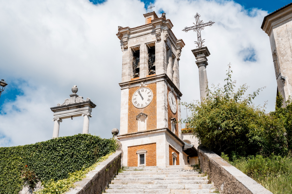 Staircase leading to the bell tower of Sacro Monte di Varese, with blue sky and surrounding greenery.