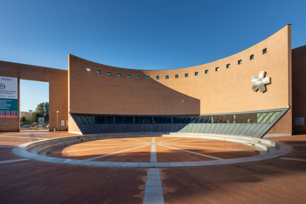 Modern facade of the MAGA in Gallarate, with a circular square in the foreground and a clear sky in the background.