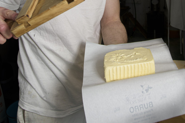 Il casaro mostra il panetto burro, risultato della lavorazione a mano e dell'utilizzo dello stampo
